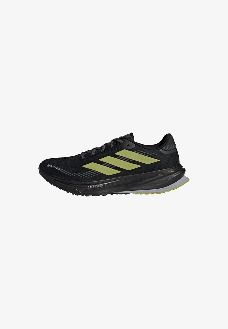 Baskets de course Adidas noires et jaunes avec un matériau Gore-Tex, une semelle rembourrée et trois rayures jaunes sur le côté.