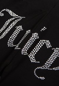 Schwarzer Stoff mit glänzenden, silbernen Strasssteinen, die in einem dekorativen Muster angeordnet sind und einen auffälligen Kontrast sowie einen strukturierten visuellen Effekt erzeugen.