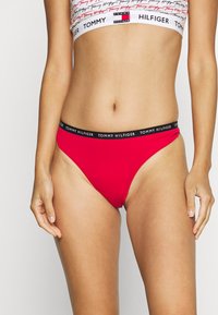 Culotte de bikini en coton rouge avec une ceinture noire arborant un texte de logo blanc répété. Conçue avec une coupe taille basse et une texture lisse.