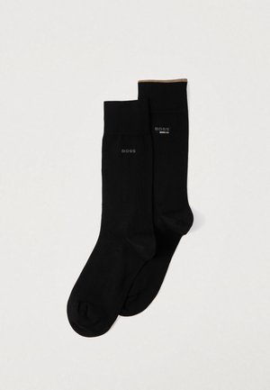 Schwarze Socken aus glattem Stoff, mit einem kontrastierenden goldenen Akzent oben und einem Markenzeichen in Grau auf der Seite gedruckt.
