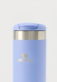 Cana de călătorie din oțel inoxidabil cu finisaj mat violet deschis, având un capac metalic argintiu și un logo auriu în relief.