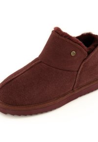 Burgundy suede slipper with a soft faux fur lining, rounded shape, stitched accents, and a textured rubber sole for grip. Gold logo detail.