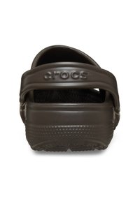 Donkerbruin Crocs klompen met een gevormd ontwerp, gesloten neus en een brede hielband, met gestructureerde zolen en het merkteken op de achterkant.