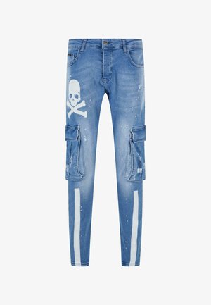 Blauwe denim cargo broek met cargozakken, doodskop en kruisbotten print, en witte verfspetters, met contrasterende witte strepen aan de zijkanten.