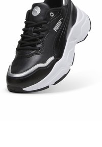 Baskets de sport noires avec une tige en cuir texturé, des accents argentés, une semelle intermédiaire blanche et une semelle extérieure en caoutchouc flexible ; elles présentent un laçage traditionnel.