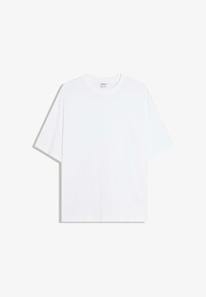 Fehér, bő szabású pamut póló kerek nyakkivágással és rövid ujjakkal; sima textúra, látható minták vagy díszítések nélkül.