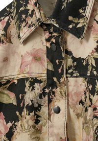 Jeansjakke med blomsterprint på sort baggrund, med pink og cremefarvede blomster, kontrastsyning og sølvfarvede trykknapper.