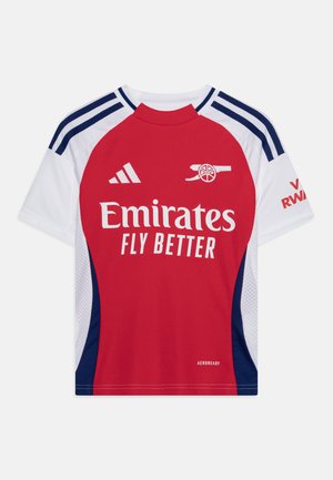Raudona ir balta trumpomis rankovėmis marškinėliai su mėlynomis detalėmis, ant krūtinės užrašas "Emirates Fly Better" didelėmis baltomis raidėmis ir Adidas logotipas.