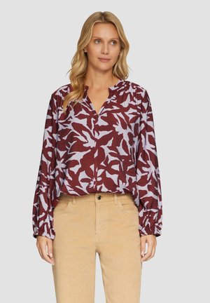 Bordeaux blouse met een lavendel abstract patroon, lange mouwen en een v-halslijn. Gepaard met tan ribfluwelen broek, met een voorste knoopsluiting.