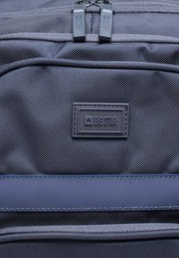 Halli kangast seljakott, millel on ristkülikukujuline plaastriga "BIG STAR" tekst, kahekordne lukk ja tekstureeritud pind. Aktsentideks on sinised õmblused.