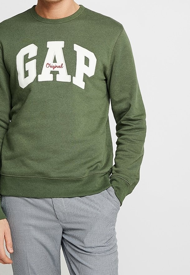 Zelená mikina vyrobená z bavlněné směsi, se bílým logem "GAP" a červeným akcentem. Klasický kulatý výstřih a žebrované manžety a lem.