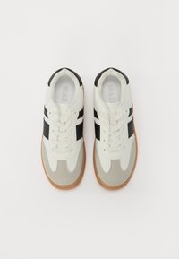 Sneakers albe și gri cu accente negre, dotate cu o talpă din cauciuc texturat, design cu șireturi și material neted. Stil sportiv clasic.