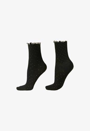 Czarne skarpetki do kostki w małe białe kropki z falbanką wzdłuż górnej krawędzi.