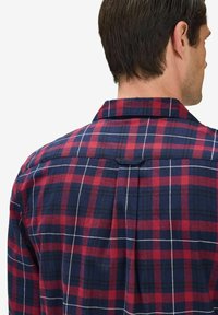 Röd och marinblå rutigt flanellskjorta med klassisk krage, knappad bakveck och kontrasterande vita linjer mellan färgerna.