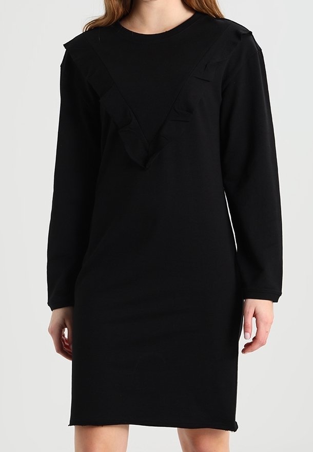 Svart långärmad klänning med V-formad halsringning prydd med volangdetaljer. Tillverkad av mjukt tyg, knälång med avslappnad passform.