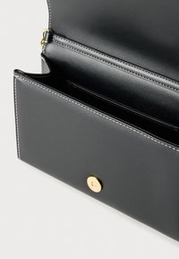 Μαύρο δερμάτινο πορτοφόλι με λευκή ραφή, που διαθέτει χρυσό κουμπί με σούστα και πολλαπλές εσωτερικές θήκες για οργάνωση.