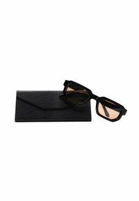 Occhiali da sole neri rettangolari con lenti oscurate posati su un astuccio nero testurizzato con un design minimalista.