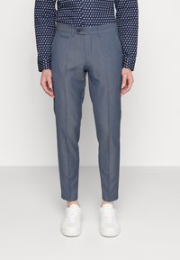 Grå skräddarsydda byxor med en mjuk textur, som har en smal passform, sidofickor och en knappstängning, i kombination med vita sneakers.