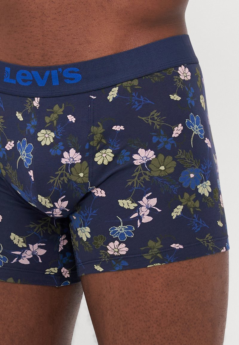 Los calzoncillos de flores de Levi's tienen una base azul marino con una variedad de flores rosas, azules y verdes. La cinturilla es de un azul marino sólido con un logo en azul.