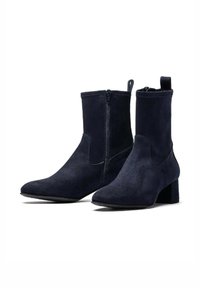Stivaletti alla caviglia in suede blu navy con tacco quadrato, zip laterale e linguetta per il pulling. Texture liscia con punta affusolata. Design minimalista.