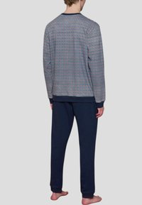 Maglietta a maniche lunghe con un motivo a quadretti nei colori blu, rosso e bianco; abbinata a pantaloni blu scuro uniformi. Il tessuto sembra morbido e il design è casual.