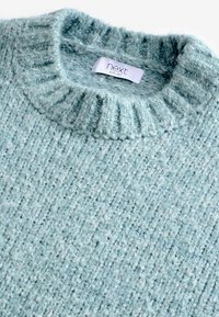 Lyseblå strikket sweater med ribbet rund hals og struktureret stof. Har et mærke mærket "next" inde i kraven.