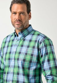 Knopfhemd mit einem mehrfarbigen karierten Muster in Grün, Blau und Marineblau. Der Stoff wirkt glatt, mit einem strukturierten Kragen und Logo.