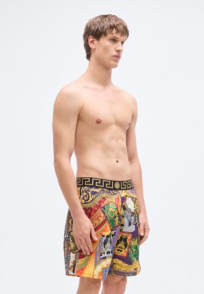 Πολύχρωμα μαγιό με σχέδια, που διαθέτουν μαύρη ελαστική μέση με χρυστό γεωμετρικό σχέδιο. Το υλικό φαίνεται ελαφρύ και λείο.