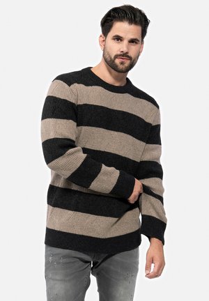 Suéter de punto con franjas alternas gruesas en negro y beige, cuello redondo y puños acanalados. Hecho de un material texturizado similar a la lana.