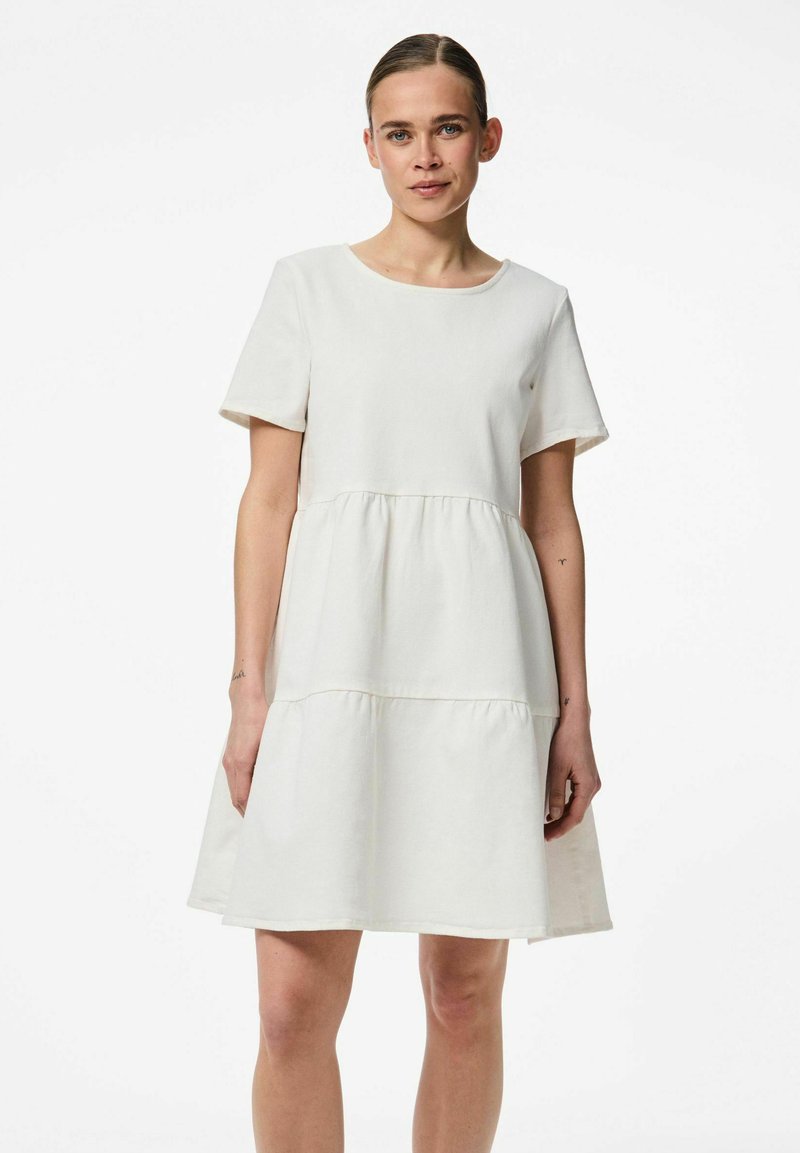 Kortärmad, elfenbensfärgad A-linjeformad klänning med rund halsringning, lagerdesign och mjukt bomullstextur, med sömdetaljer vid midjan.