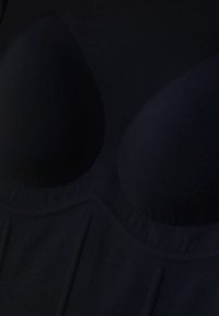 Primo piano di coppe di reggiseno nere imbottite con dettagli di cucitura arricciata lungo il bordo sotto le coppe.
