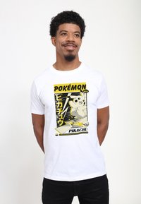 Bílé bavlněné tričko s černým a žlutým motivem Pikachu v retro stylu Pokémonů, včetně textu a bleskových akcentů.