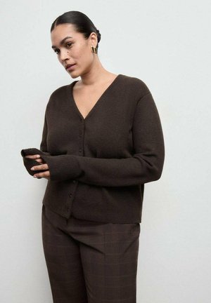 Cárdigan de punto marrón con escote en V, cierre de botones y puños acanalados. Combinado con pantalones marrones a cuadros, resaltando un aspecto texturizado.