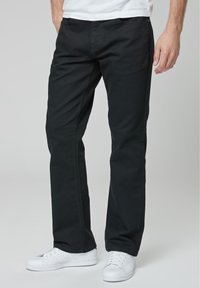Zwarte katoen broek met een recht ontwerp, met riemlussen en voorkruiszakken, gecombineerd met witte sneakers. Gladde stofstructuur.