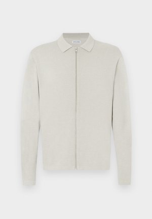 Cardigan de malha bege claro de manga comprida com gola e fecho de correr frontal, exibido sobre um fundo branco e plano.