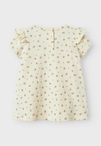 Robe fleurie jaune avec des manches courtes à volants, dotée d'une fermeture à boutons dans le dos, en tissu texturé avec un design en relief et de petits motifs floraux.