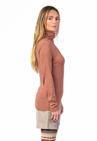 Langarm-Turtleneck aus rostfarbigem Stoff, figurbetontes Design, glatte Textur, kombiniert mit einem hellen Cordrock und gestreiften Kniestrümpfen.