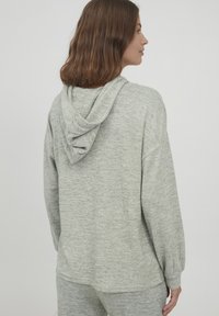 Světle šedá mikina s kapucí, volného střihu, vyrobená z měkké, strukturované tkaniny. Disponuje dolman rukávy a klokankovou kapsou.