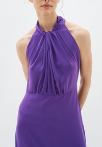 Rochie halter de culoare mov, cu material drapat la guler și o siluetă netedă, ajustată. Material ușor, cu o textură moale.
