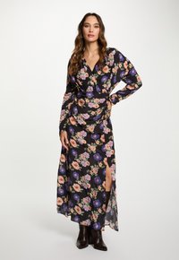 Lang zwart jurk met bloemenprint in roze, oranje en paars. Bevat lange mouwen en een zijsplit. Gemaakt van lichte stof.