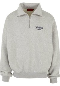 Sudadera gris con media cremallera, puños y cintura acanalados, que presenta "Prendas Prohibidas" bordado en azul marino en el lado izquierdo del pecho.