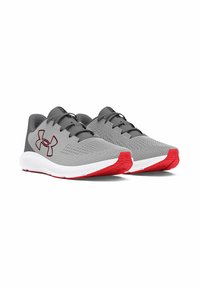 Baskets de sport grises avec un dessus en tissu texturé, des accents rouges et des semelles intermédiaires blanches. Dotées de lacets noirs et d'un logo proéminent sur le côté.