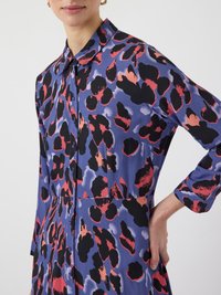 Printed dress featuring a bold pattern of black, red, and blue abstract shapes. Slim fit, button-front design with long sleeves.