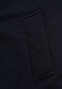 Musta kangas, jossa on tasapocket ja ompeluyksityiskohtia, esittelee sileän tekstuurin ja yksinkertaisen, funktionaalisen muotoilun.