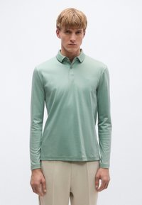 Hosszú ujjú, világoszöld pamut póló galléros nyakkivágással és finom logóval a mellrészen. Sima textúrájú, karcsúsított fazon.