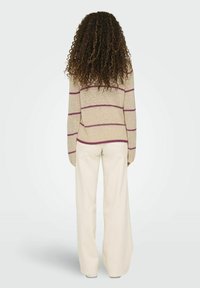 Beige gestreepte trui met paarse lijnen, losse pasvorm, geribbelde manchetten, gecombineerd met wijdvallende crèmekleurige broek. Gebreide textuur, achterkantzicht.