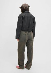 Veste courte en simili cuir noir, jeans verts à coupe décontractée et chaussures roses. Dispose d'un col, d'une ceinture élastique et de poches sur le pantalon.