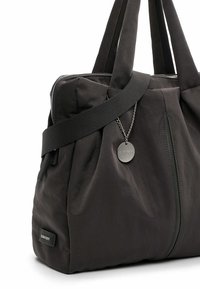 Black nylon tote bag with a zip closure, pleated design, detachable shoulder strap, and a metal logo tag attached by a chain.