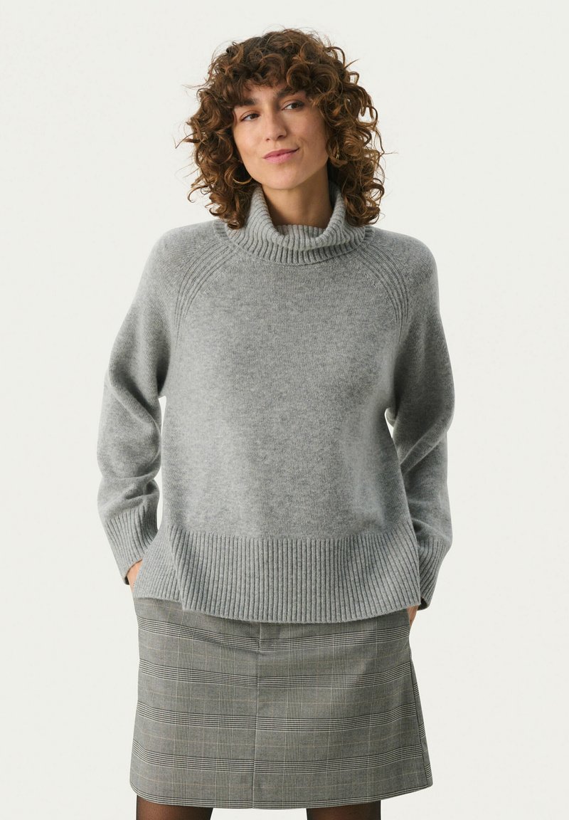 Grå turtleneck sweater med ribbet kant og manchetter, der har en blød striktekstur. Sammen med en grå ternet nederdel.