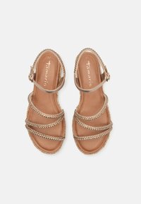 Sandales plates métalliques dorées pour femmes taille 37 avec trois brides à l'avant et une bride de cheville avec boucle, marquées "Tamaris" sur la semelle.